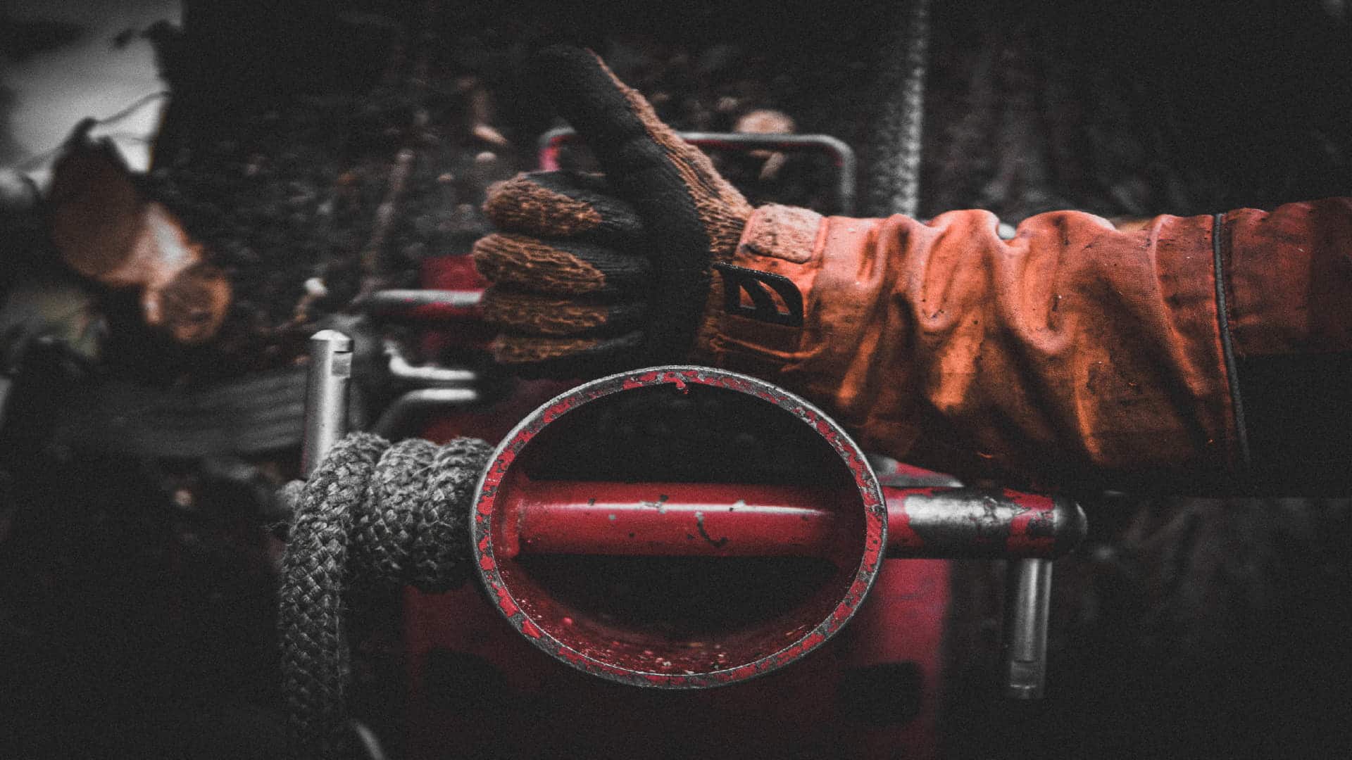 Gloved hand giving a thumbs-up near forestry equipment in a workshop setting.